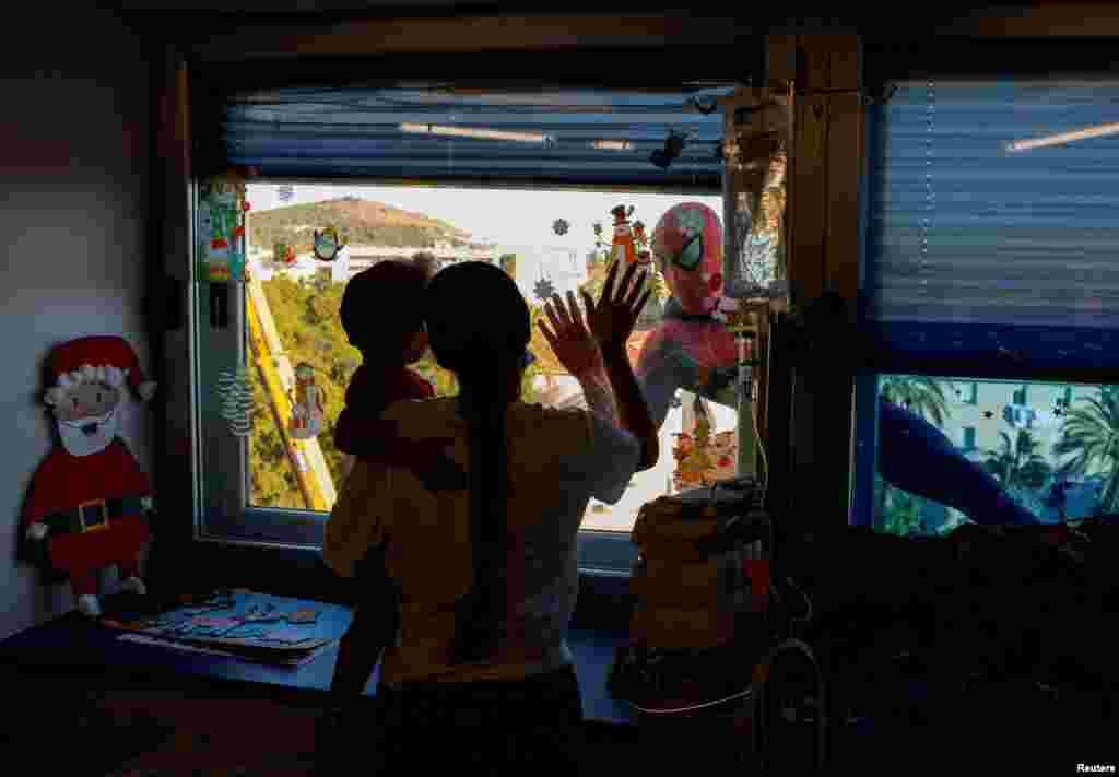 Eduardo Rodriguez, 34, a Spanish police officer, known as Edu Balboa, dressed up as Spiderman, waves at a girl and her aunt as he visits children with cancer through the windows at the Materno Infantil hospital in Malaga, Spain.
