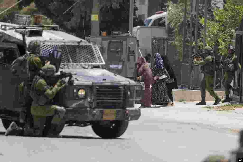 Israeli soldiers escort female relatives of a wanted Palestinian man out of his besieged house in the West Bank Town of Urif.