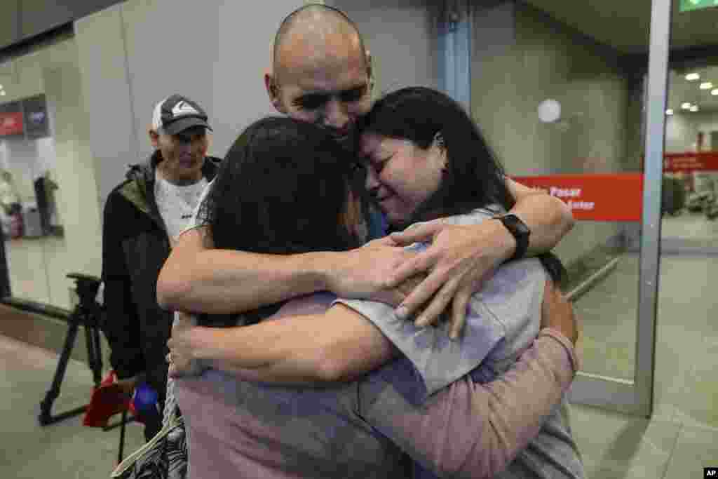 Sean Ours, center, who lives in Alexandria, Virginia, and Emily Reid, right who lives in Raleigh, NC, embrace for the first time their biological mother Sara Melgarejo upon their arrival at the airport in Santiago, Chile.