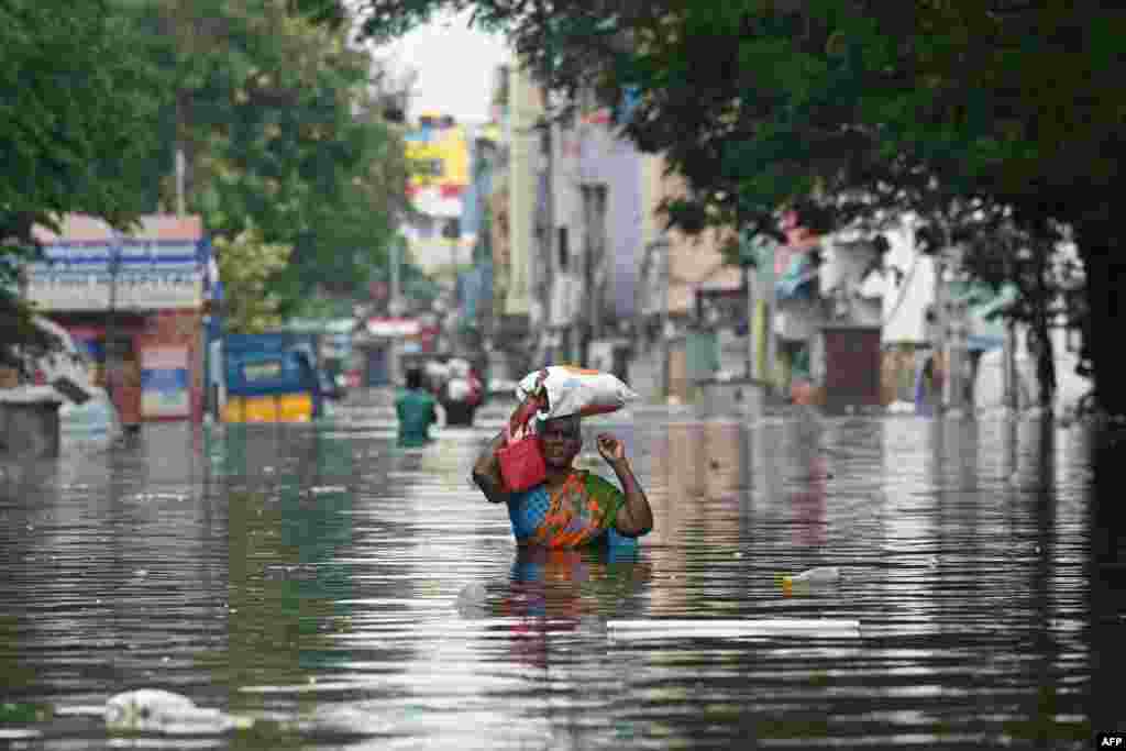 A woman along with her belongings, wades through a flooded street after heavy rains in Chennai, India. Chest-high water surged down the streets of Chennai with eight people killed in intense floods as Cyclone Michaung made landfall on the southeast coast. 