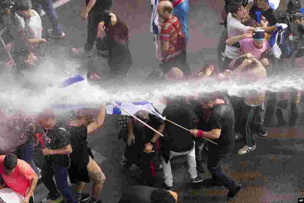 Police use a water cannon to disperse Israelis blocking the freeway during a protest against plans by Prime Minister Benjamin Netanyahu's government to overhaul the judicial system in Tel Aviv.