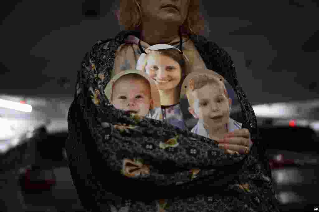 A woman holds a mask depicting the faces of Shiri Bibas and her sons Kfir and Ariel, Israelis who are being held hostage in the Gaza Strip by the Hamas militant group, during a protest demanding the release of the hostages, in Tel Aviv.