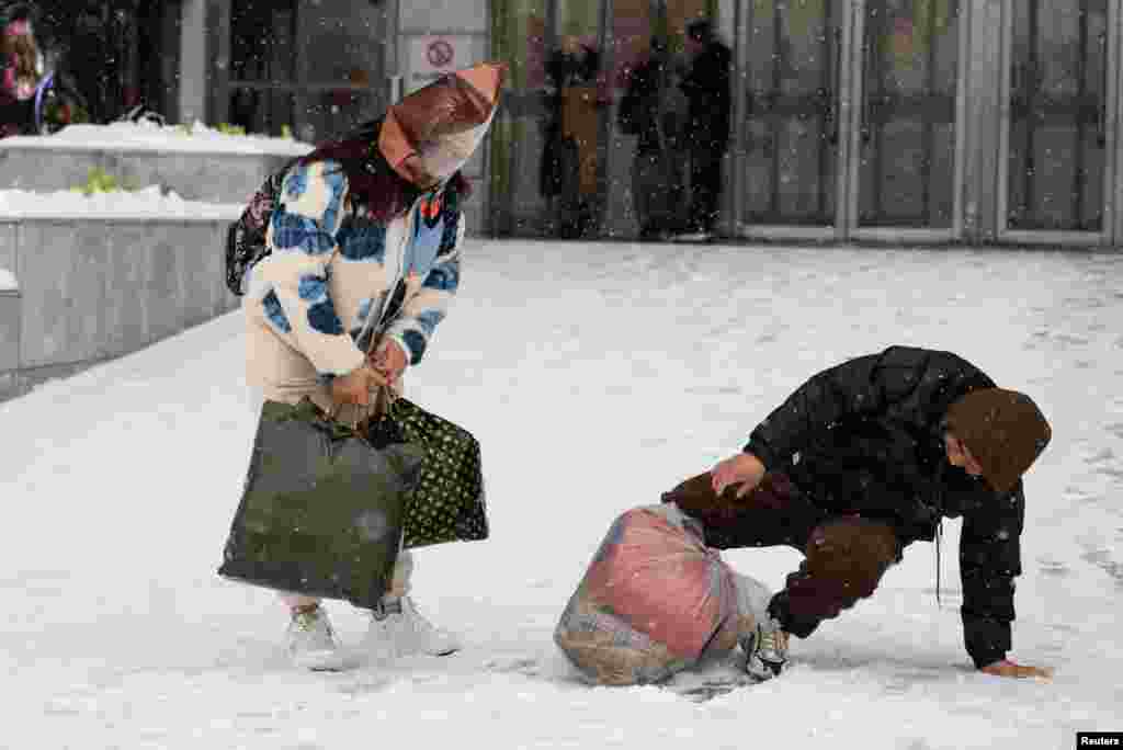 A man falls on a slope amid snowfall in Beijing, China.