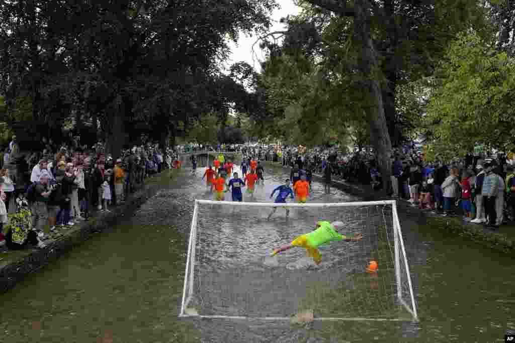 Footballers from Bourton Rovers fight for the ball during the annual traditional River Windrush football match in the Cotswolds village of Bourton-on-the-Water, England.