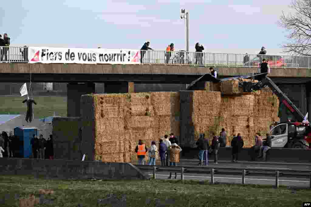 A banner reading "Proud to feed you !" is seen at a road blockage held by farmers on the A4 highway near Jossigny, east of Paris, amid nationwide protests called by several farmers unions on pay, tax and regulations.