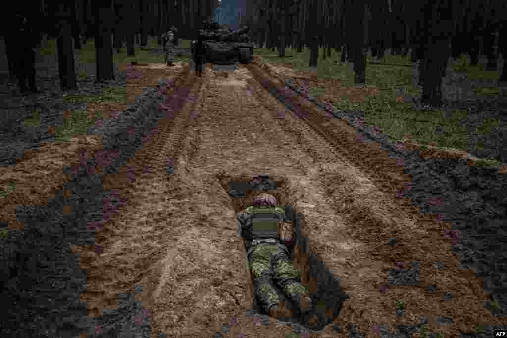 A Ukrainian serviceman lies in a trench during a military exercise in the Kharkiv region, May 1, 2023, amid the Russian invasion of Ukraine.