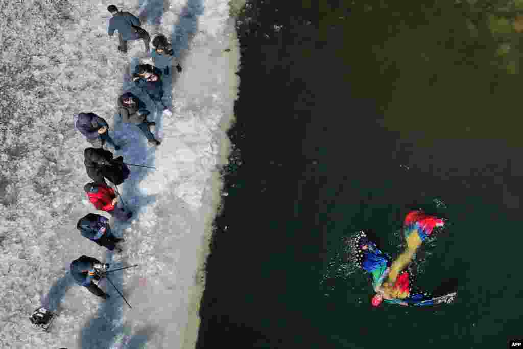 A woman dressed in a mermaid swims in a partly frozen lake in Shenyang, in northeastern China's Liaoning province.