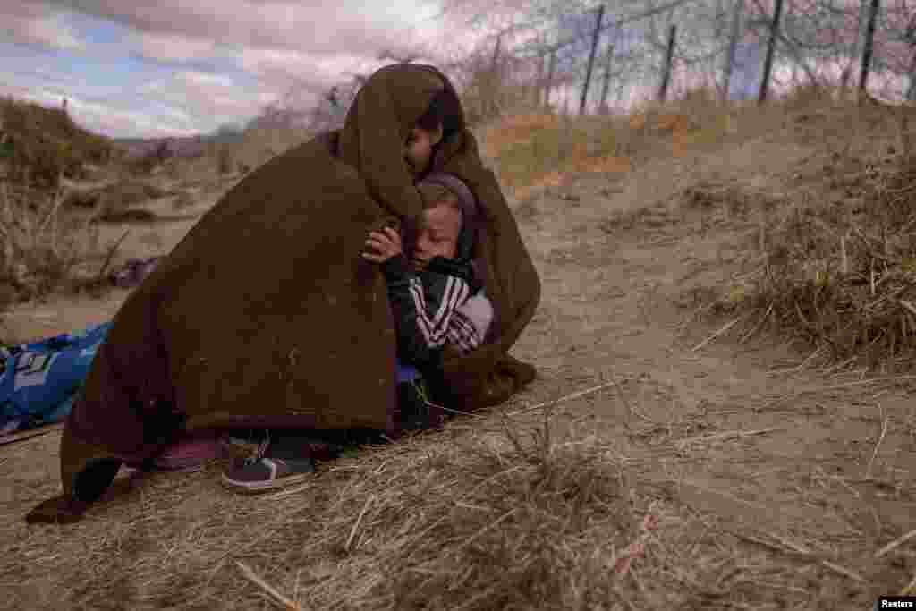 Jolimar, an 18-year-old migrant from Venezuela, shelters her two-year-old son Gail from the cold and blustery weather as they search for an entry point into the U.S. along the bank of the Rio Grande river in El Paso, Texas, March 25, 2024.