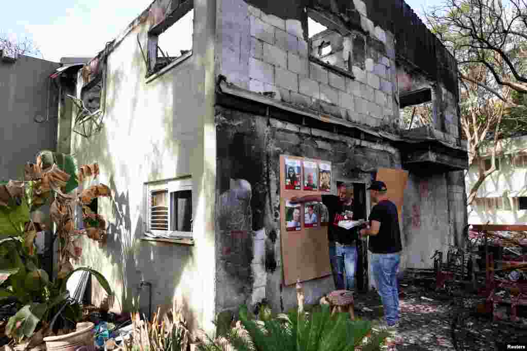 Supporters place placards of hostages who are held by Palestinian Islamist group Hamas on the wall of a damaged house, as they visit Kibbutz Beeri, Israel, to demand their immediate release.