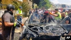 Travayè Defans Sivil yo enspekte sak rete de yon machin ki boule nan yon frap ayeryen Izrayelyen nan vil Sidon, Liban, 26 Out, 2024.