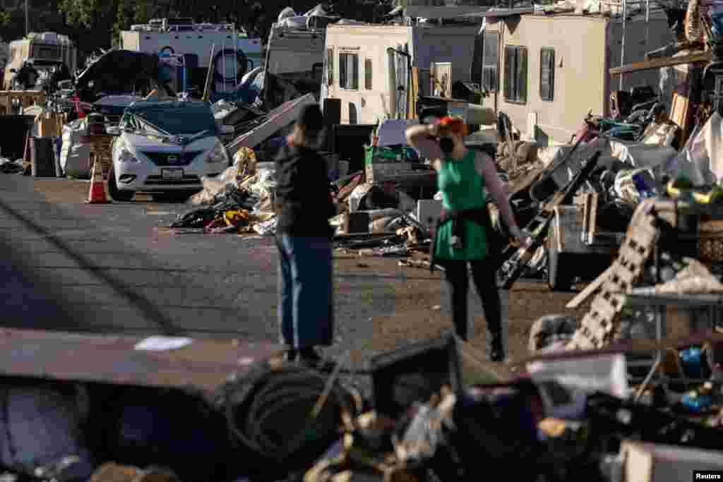 Volunteers help to clean up belongings at an encampment of homeless people near the Nimitz Freeway in Oakland, California, April 2, 2024, after the city issued an order to remove and clean up the area where between 30 to 40 people live in cars, RVS, tents, and other makeshift structures.