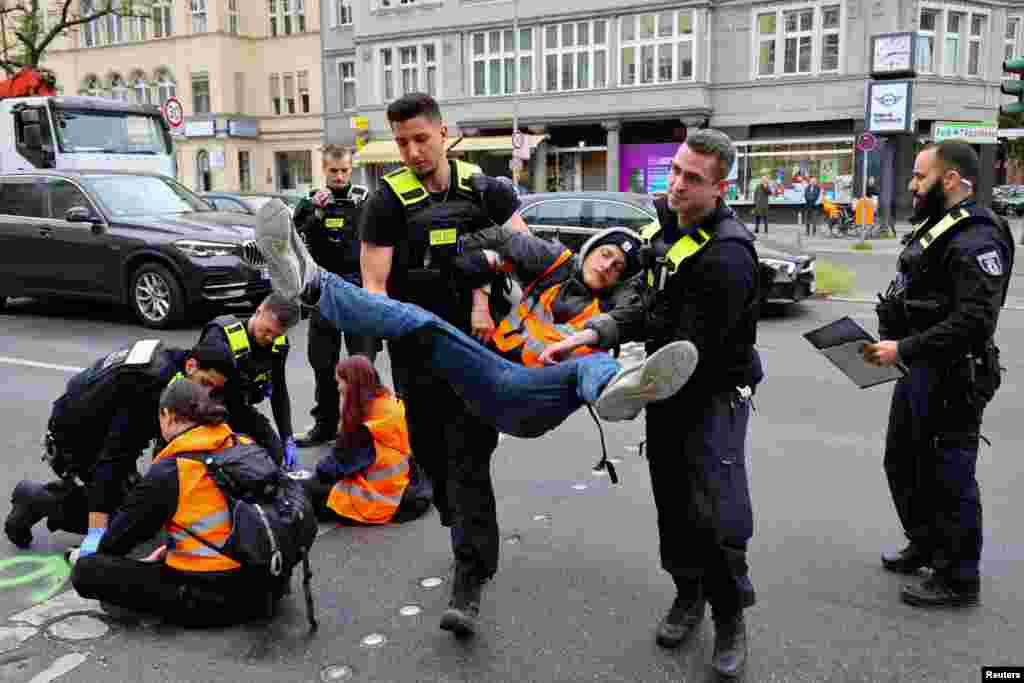 Police officers carry away an activist of the "Letzte Generation" (Last Generation), who previously glued himself to a street at Steglitz district to protest for climate councils, a speed limit on highways as well as for affordable public transport, in Berlin, Germany.