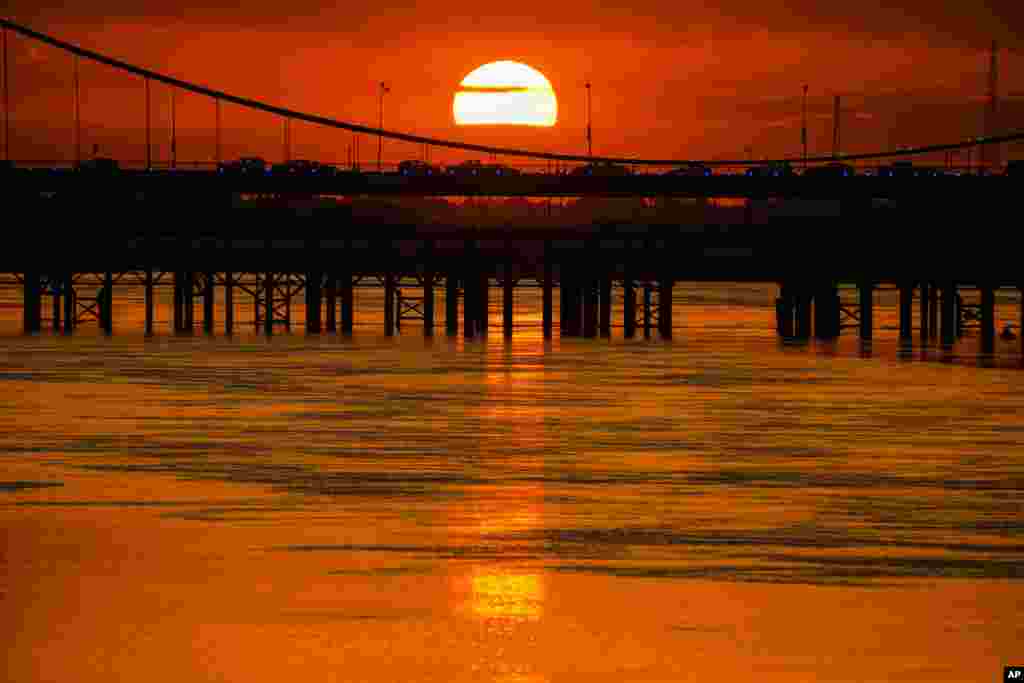 The sun sets behind a suspension bridge over the Tigris River in Baghdad, Iraq.