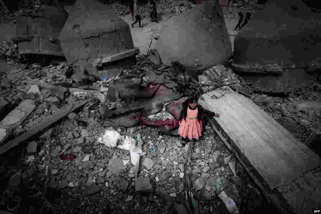 A Palestinian girl wearing a pink dress stands amidst the ruins of the Al-Faruq Mosque that was destroyed during Israeli bombardment, in Rafah on the southern Gaza Strip.