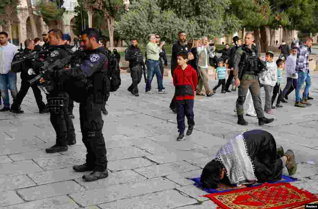 Members of the Israeli security forces stand near Palestinian people praying at the Al-Aqsa compound, also known to Jews as the Temple Mount, in Jerusalem's Old City.