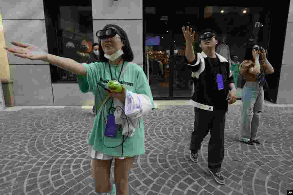 Visitors to a mall grasp at air as they try out an augmented reality experience of a digital art gala in Beijing, China.