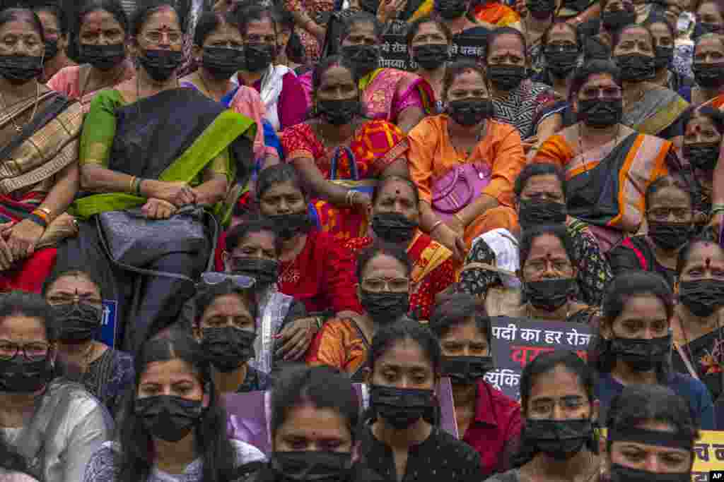Supporters of Shiv Sena wearing black masks sit during a silent protest seeking an end to violence against women, in Mumbai, India.