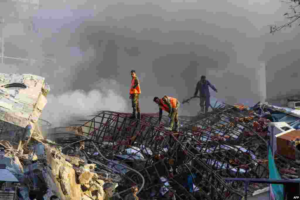 Emergency personnel extinguish a fire at the site of strikes which hit a building in Syria's capital Damascus. Syrian state media said Israeli strikes destroyed the Iranian consular section.