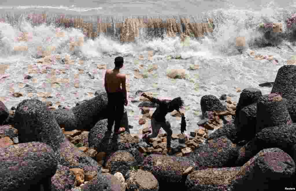 Boys watch waves hit the shore in Mumbai, India.