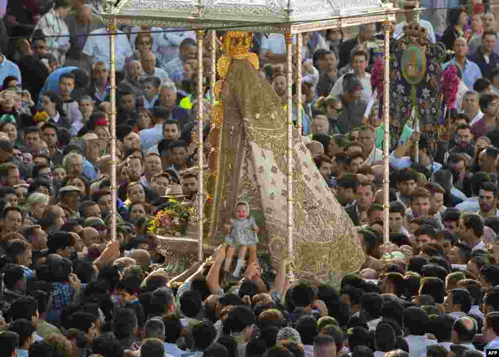 Pilgrims place a baby against the effigy of the Rocio Virgin outside the hermitage in El Rocio village in the Andalusian province of Huelva, Spain, during the annual pilgrimage of El Rocio.