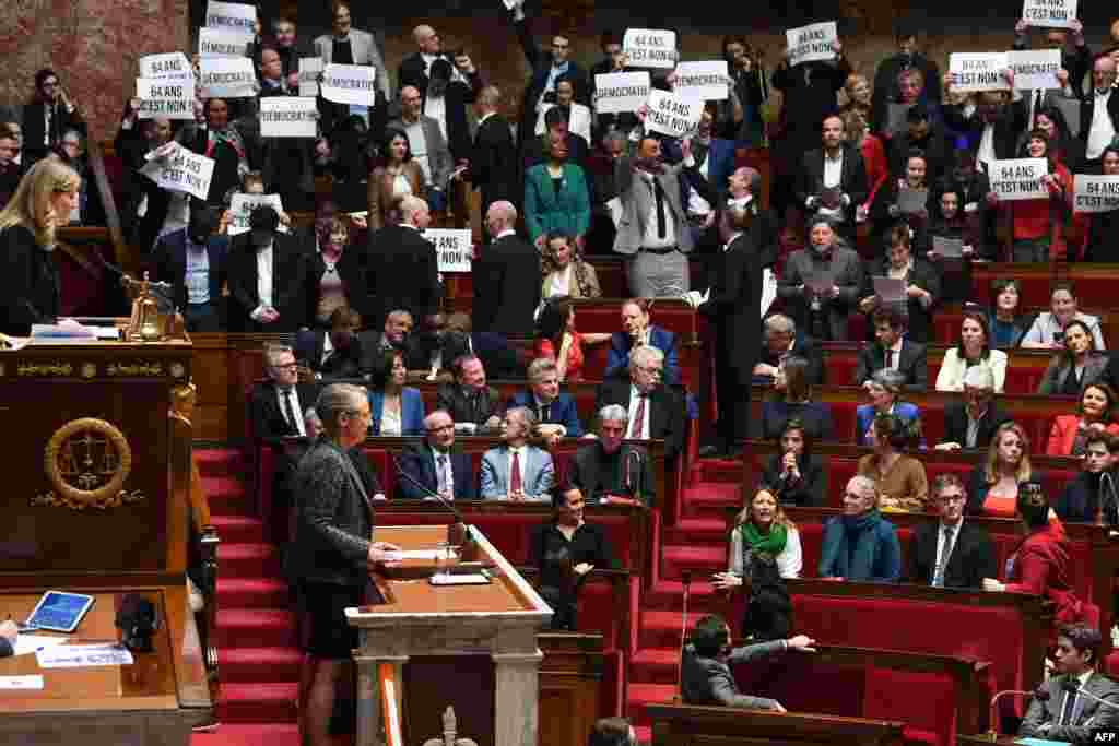 Members of left-wing coalition NUPES (New People's Ecologic and Social Union) hold placards during the speech of France's Prime Minister Elisabeth Borne (C), as she confirms to force through a proposed pension bill without a parliament vote during a session regarding the government's pension reform at the lower house National Assembly, in Paris.