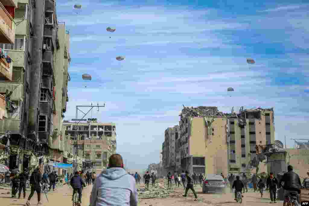 Palestinians run along a street as humanitarian aid is air-dropped in Gaza City, amid the ongoing conflict between Israel and the Hamas militant group. For months, aid workers have warned of an increasingly desperate situation for civilians in the area.