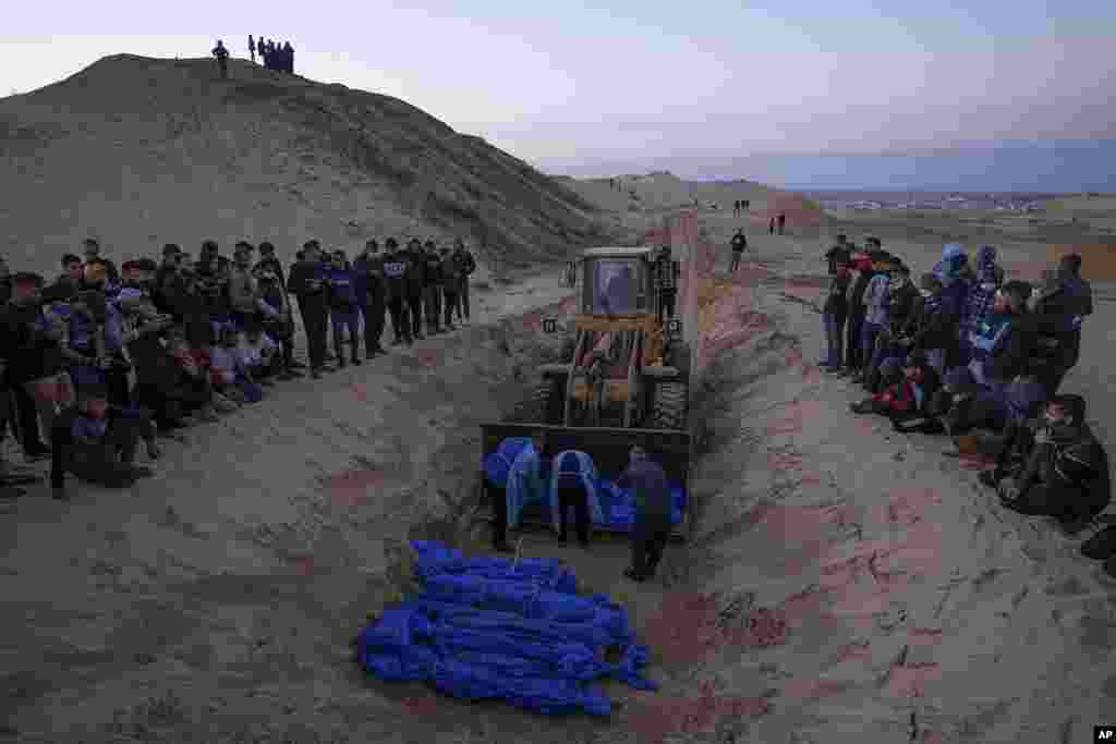 A bulldozer unloads the bodies of Palestinians killed in fighting with Israel and turned over by the Israeli military, during a mass funeral in Rafah, Gaza Strip.