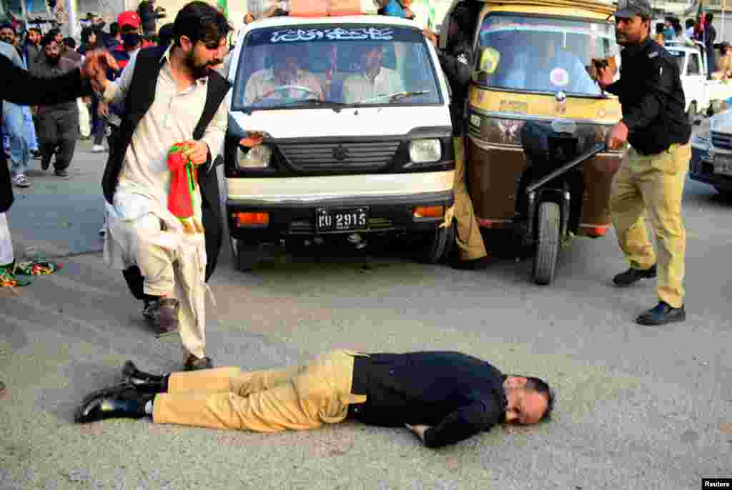An injured police officer lies on the road during a clash with supporters of former prime minister Imran Khan's party, the Pakistan Tehreek-e-Insaf (PTI), at a rally ahead of a general election, in Karachi, Jan. 28, 2024.