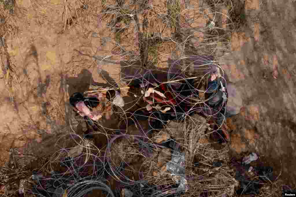 A migrant child crawls out through concertina wire along the banks of the Rio Grande River while crossing from Mexico into Eagle Pass, Texas, U.S., Dec. 19, 2023.