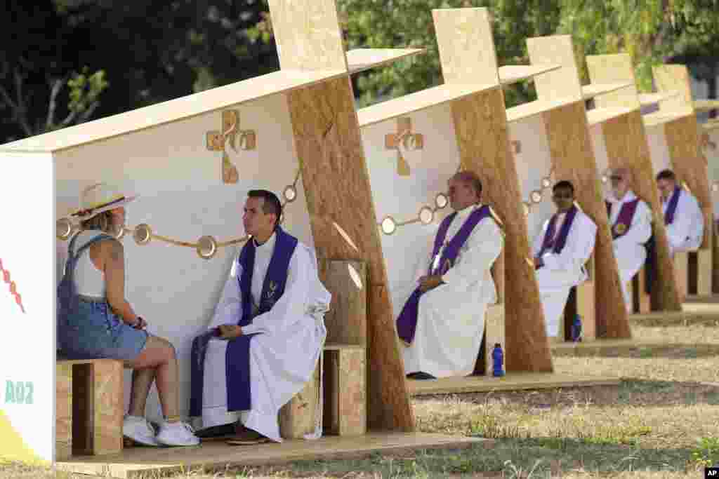 A row of priests listen to confessions for pilgrims arriving for international World Youth Day, at a park in Lisbon, Portugal.