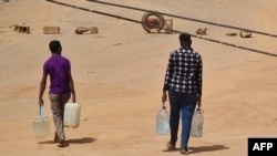 Wanaume wakikirejea majumbani mwao wakiwa na chupa za maji wakati mapigano yalipopungua huko Khartoum, tarehe 25 Mei 2023. Picha na AFP. 