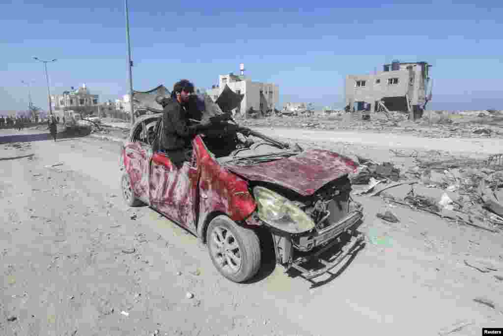 A Palestinian man rides in a damaged car in Hamad City following an Israeli raid, in Khan Younis in the southern Gaza Strip.