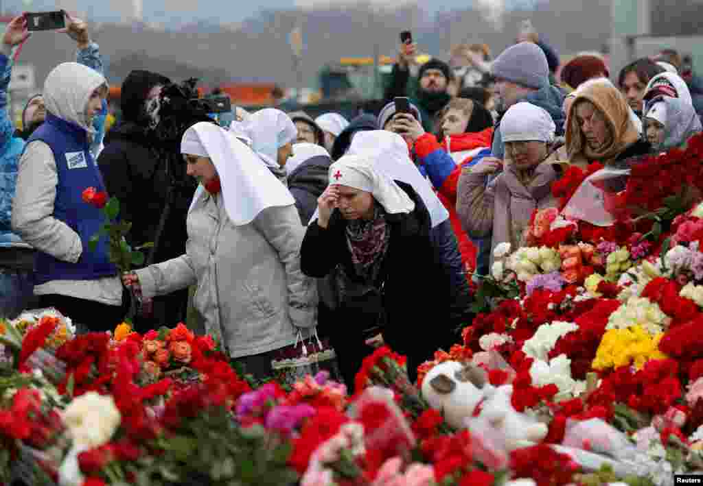 People lay flowers at a makeshift memorial to the victims of a shooting attack set up outside the Crocus City Hall concert venue in the Moscow Region, Russia.