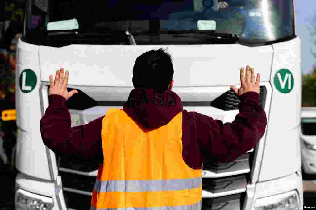 An activist of the "Letzte Generation" (Last Generation) stops a vehicle during a protest for a speed limit on highways as well as for affordable public transport, in Vienna, Austria.