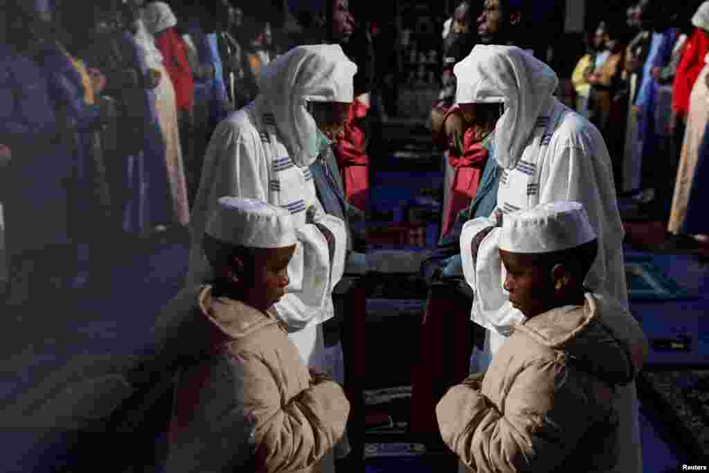 The reflection of a man and a boy is seen as people pray outside the Masjid At-Taqwa mosque on the sidewalk, during Eid al-Fitr, in the Bedford-Stuyvesant section of the Brooklyn borough of New York City, New York.
