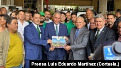 Luis Eduardo Martínez, candidato presidencial de la fracción judicializada de Acción Democrática, en el centro de la gráfica, recibe el apoyo del aspirante del partido Copei judicializado Juan Carlos Alvarado, a su izquierda, en el CNE, el 22 de abril de 2024.