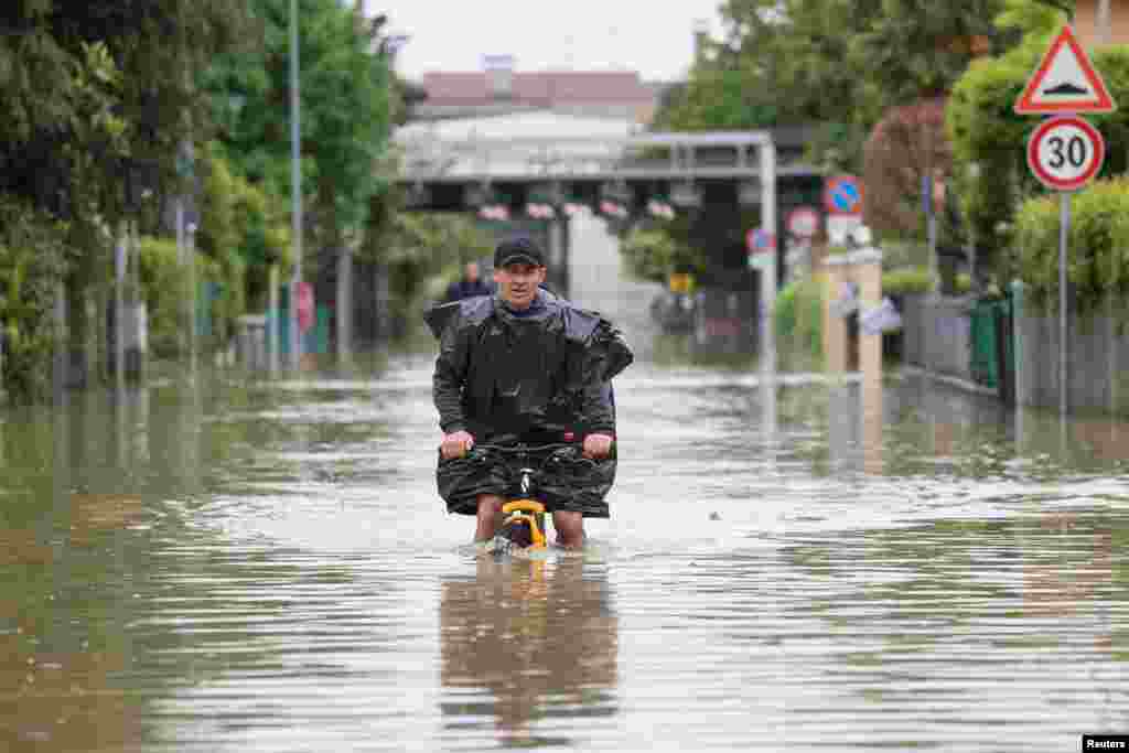 A man rides on a bicycle through floodwaters after heavy rains hit Italy's Emilia Romagna region, in Lugo, Italy.