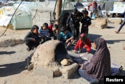 Palestinka peče hleb dok deca sede oko nje, dok se stanovnici Gaze suočavaju sa krizom gladi, u Kan Junisu, na jugu Pojasa Gaze, 24. januara 2024.