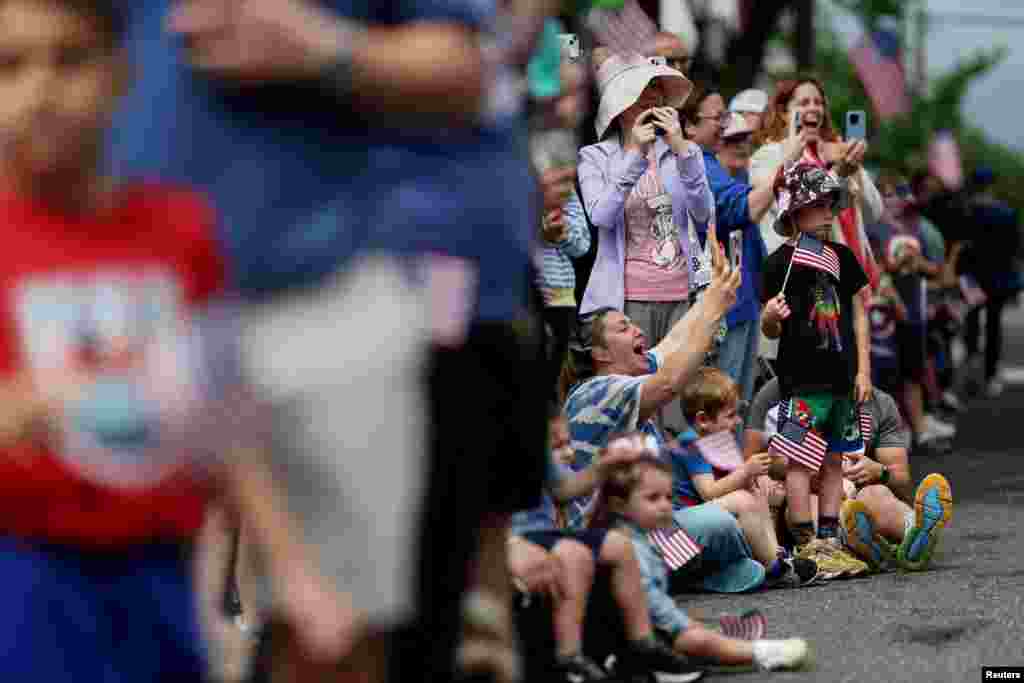Al desfile que se realiza en Port Washington en homenaje a los soldados caídos en combate, asisten niños y adultos que portan banderas de Estados Unidos. 