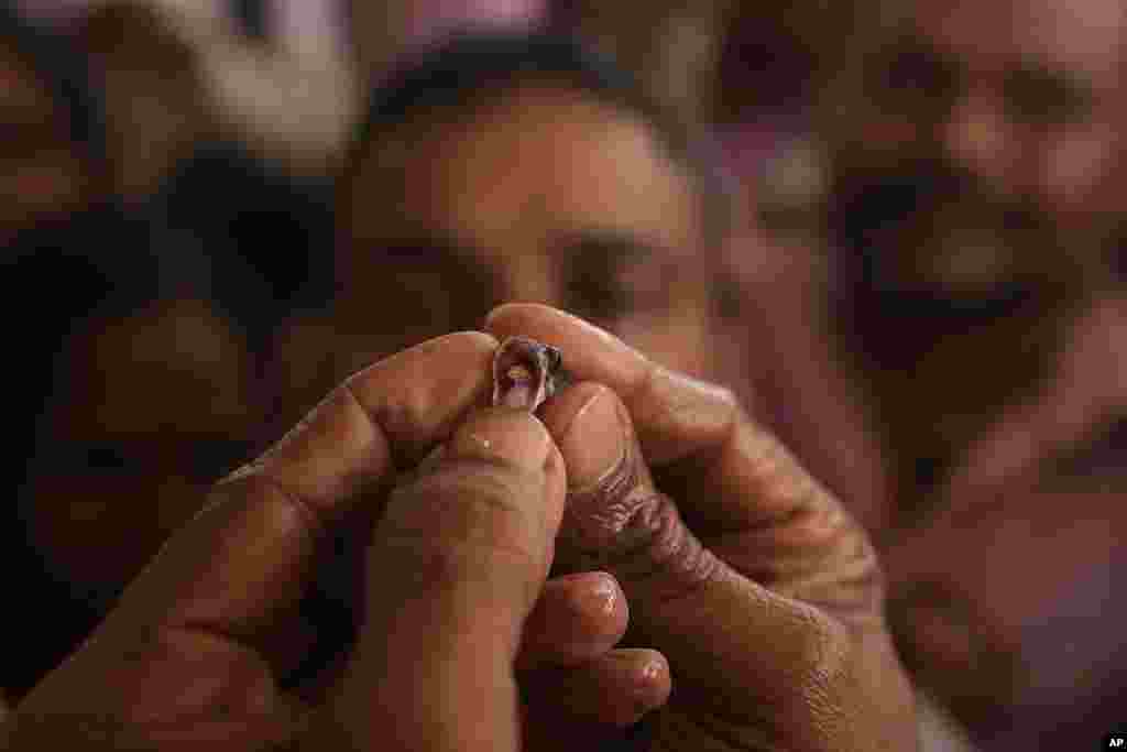 A member of the Goud family opens a fish's mouth to insert herbal medicine before administering it to a patient, in Hyderabad, India. Every year thousands of asthma patients arrive to receive the fish therapy from the Bathini Goud family, a secret formula of herbs, handed down by generations only to family members. The herbs are inserted in the mouth of a live sardine, or murrel fish, and slipped into the patient's throat.