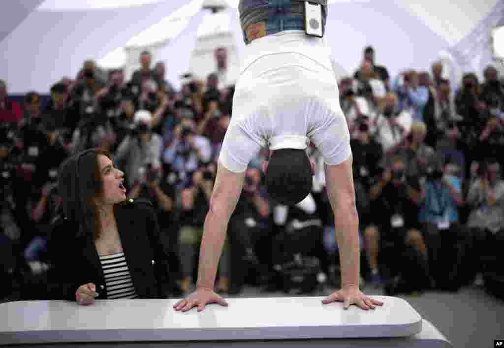 Billie Blain, left, reacts as Tom Mercier performs a handstand at the photo call for the film 'Le Regne Animal' at the 76th international film festival, Cannes, southern France.