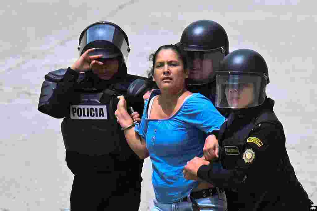 A woman is arrested as voters are dispersed by security forces outside a polling station which remains closed following alleged threats and irregularities during general elections, in San Jose del Golfo, on the northern outskirts of Guatemala City, June 25, 2023. 