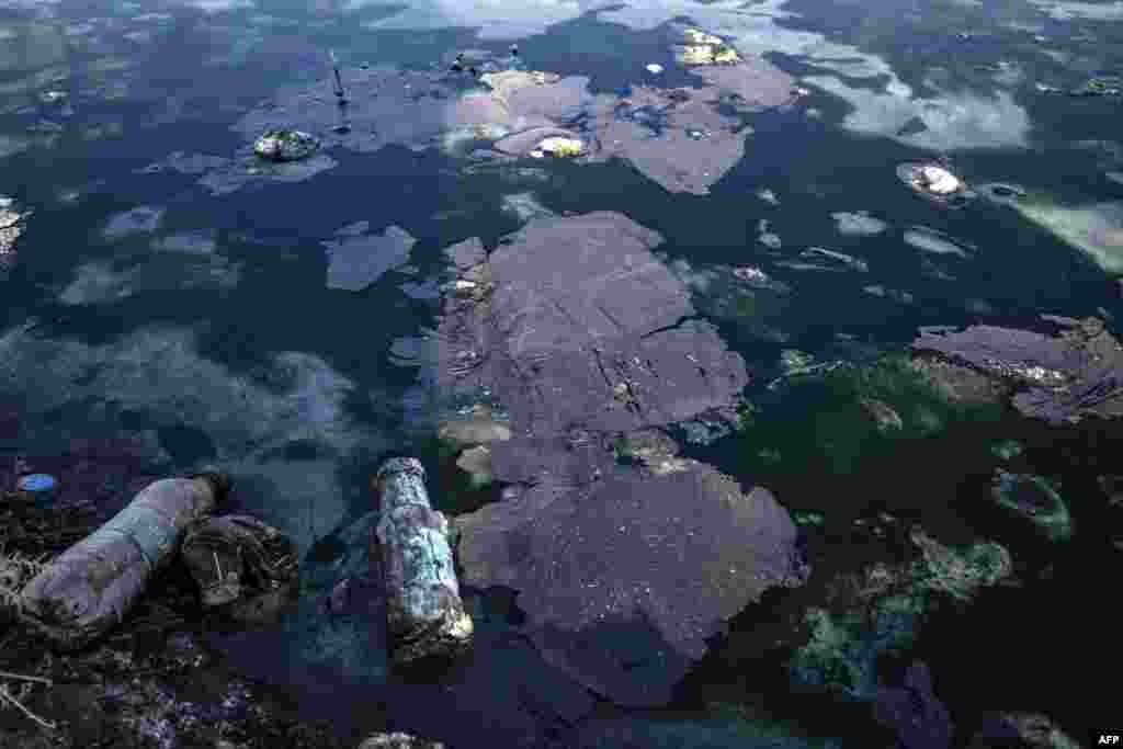 Oil and plastic bottles litter a river polluted by a nearby oil field in the countryside of Rmeilan, in Syria's northeastern Hasakeh province.