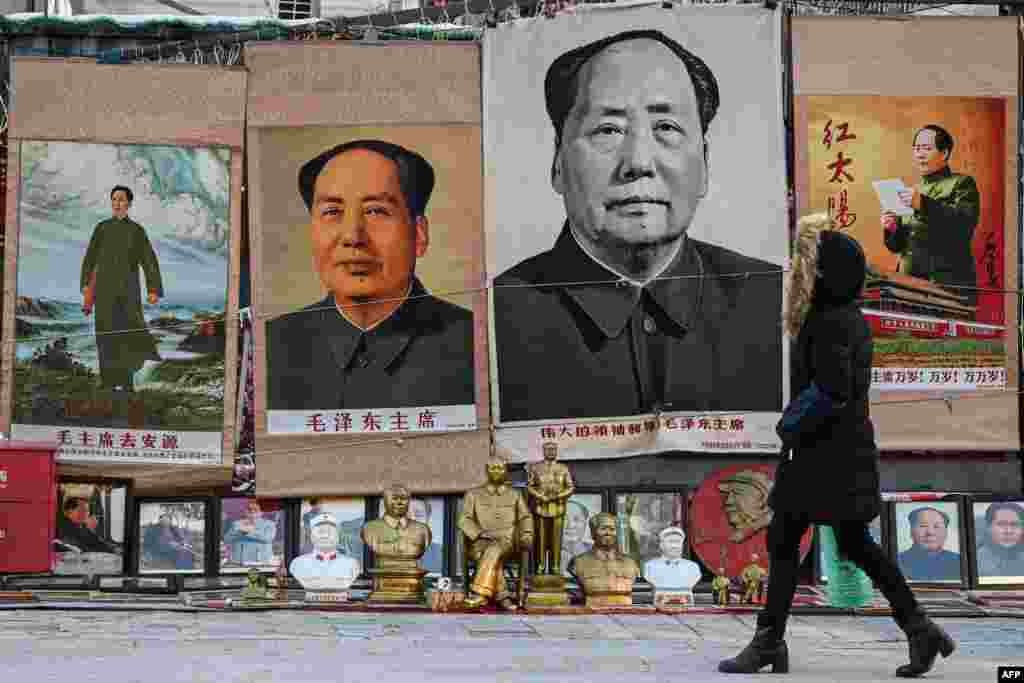 A woman walks past images depicting the late Chinese Communist leader Mao Zedong at a stall in an antique market in Beijing, on the 130th birth anniversary of communist China's founding father.