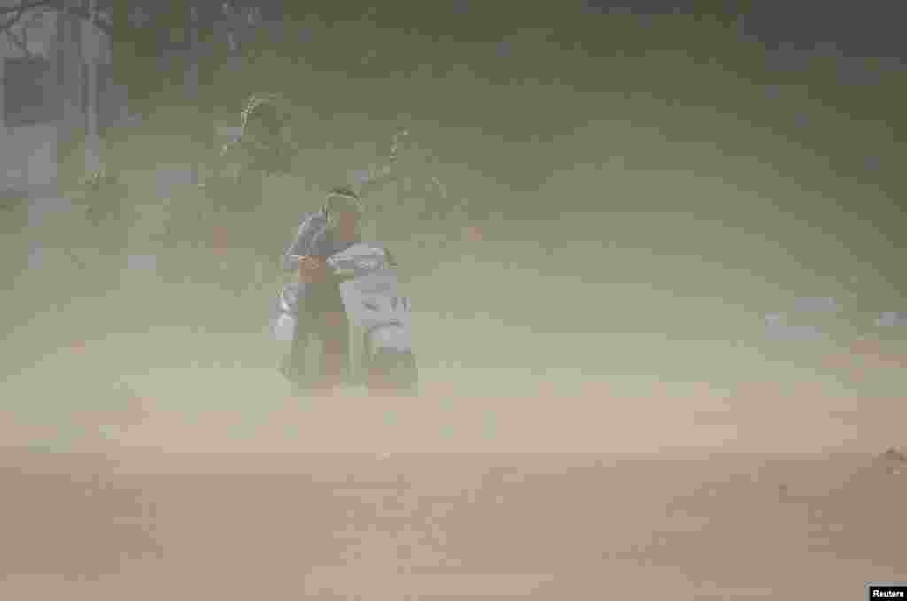 A couple rides a scooter amid dust due to strong wind, before the arrival of cyclonic storm Biparjoy, in Ahmedabad, India.