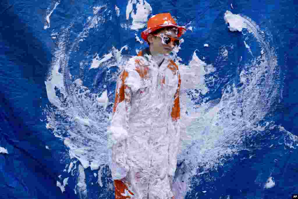 An orange-clad boy waits for people to pay to throw pies during King's Day celebrations in Amsterdam, The Netherlands. The Netherlands celebrated the 56th birthday of King Willem-Alexander of the House of Orange with street markets, parties and pastries, even as polls showed the monarch's popularity declining. 