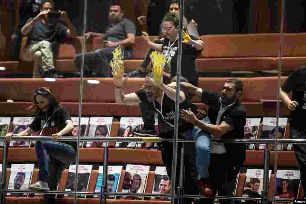 Families and supporters of hostages, kidnapped during the deadly October 7 attack on Israel by Palestinian Islamist group Hamas, smear yellow paint on glass during a demonstration at the Knesset, Israel's parliament in Jerusalem.