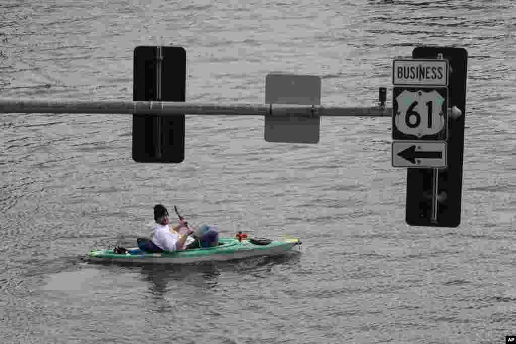 A kayaker floats down a flooded street, May 1, 2023, in downtown Davenport, Iowa.
