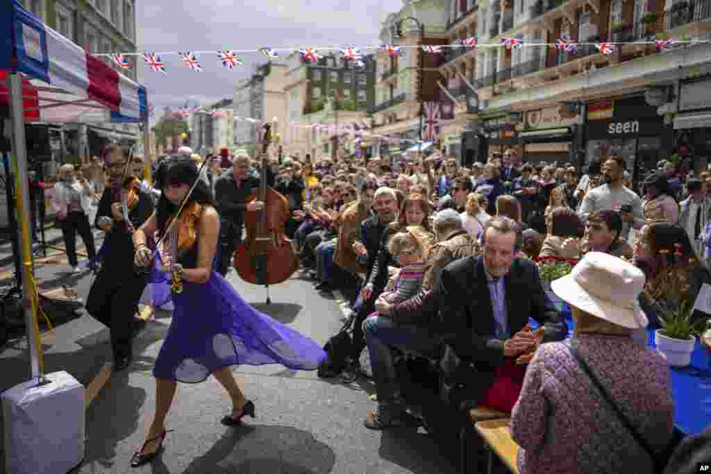 Musicians play their instruments as people sit at long tables to eat their lunch as part of the Big Lunch celebration in London. The Big Lunch is part of the weekend of celebrations for the Coronation of King Charles III.