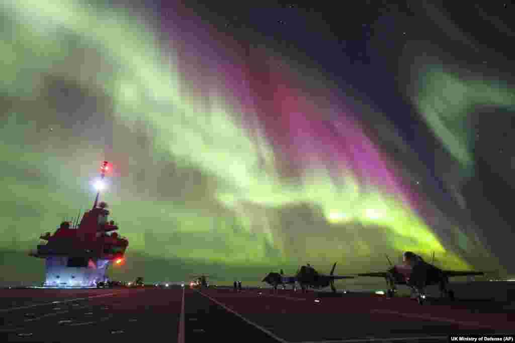 In this photo provided by Britain's Ministry of Defense, F-35B Lightning jets are parked at a flight deck of HMS Prince of Wales aircraft carrier of the Royal Navy, under the northern lights (Aurora Borealis) near the coast of Norway, March 3, 2024.